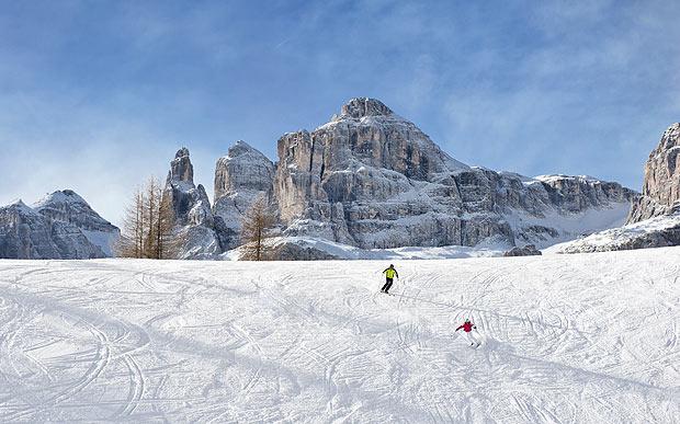 People skiing on a piste in Corvara with a backdrop of the Dolomites